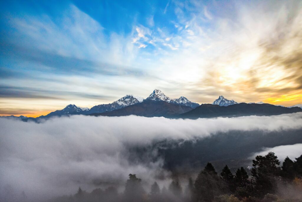 "Sunset over the Annapurna Massif featuring the iconic Machhapuchhre (Fishtail) peak rising above a sea of clouds in Nepal."